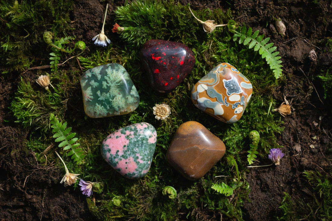 Five grounding crystals arranged on moss and earth for Earth Day