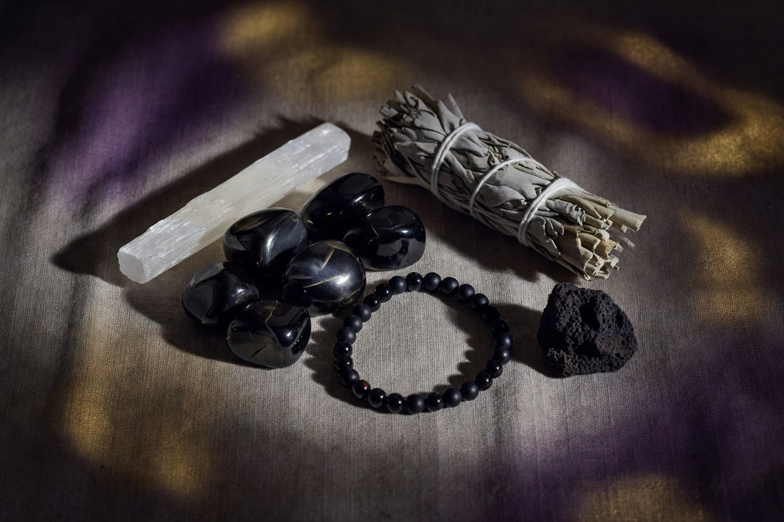 Polished black obsidian stones and bracelet on linen with sage and selenite