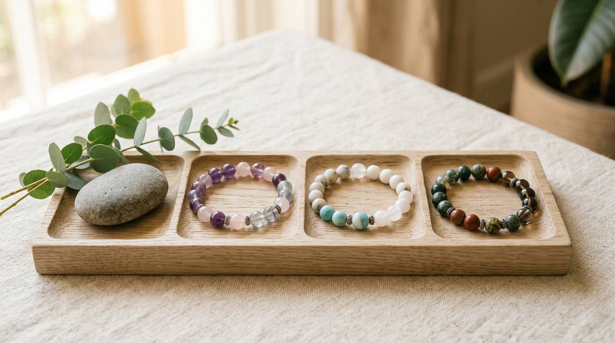 Three crystal bead bracelets arranged in a wooden tray on cream linen