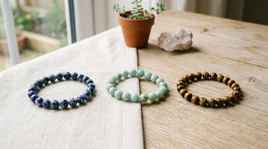 Three natural stone bead bracelets on linen and pale wood