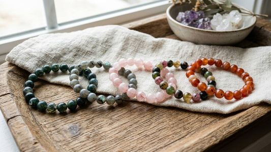 Natural gemstone bead bracelets with varied colors and markings on linen and a wooden tray
