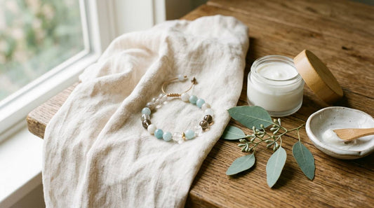 Natural stone bracelet, plain cream jar, linen, and eucalyptus by a window