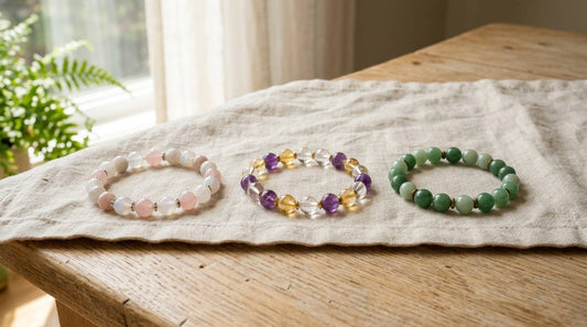 Three gemstone bead bracelets arranged on linen beside a sunlit window