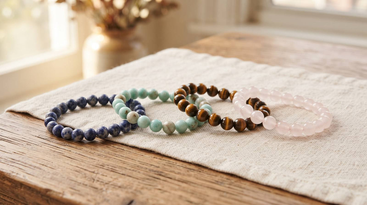 Four crystal bead bracelets in blue, green, golden brown, and pale pink on linen