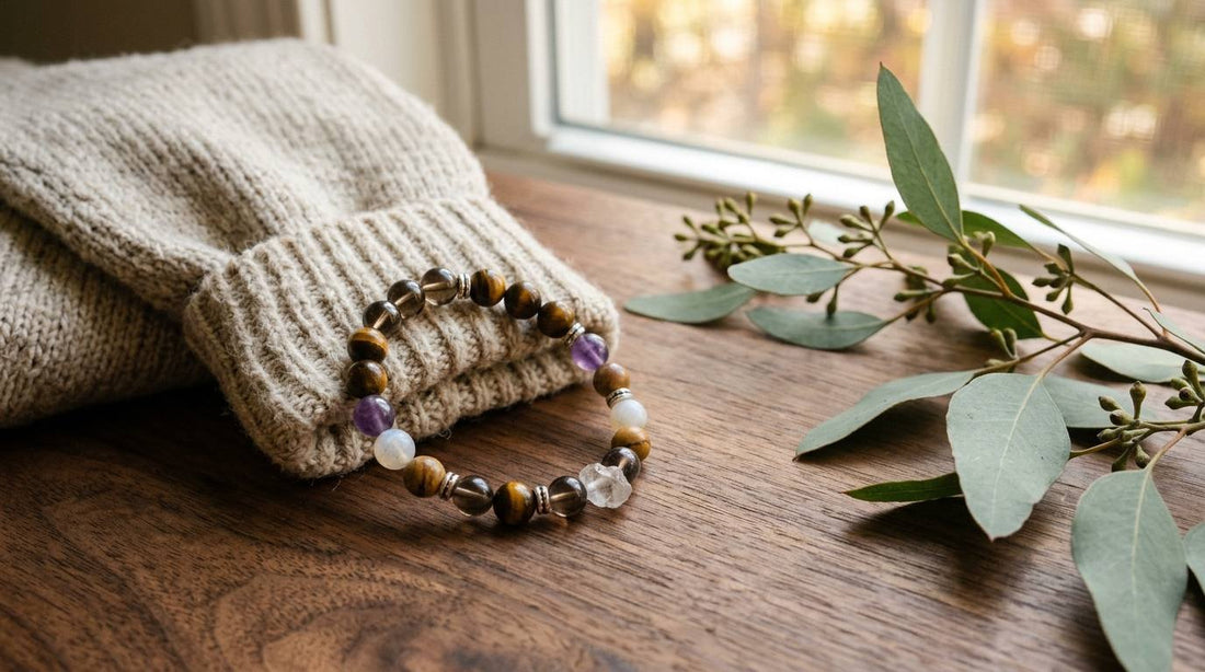 Tiger eye and crystal bead bracelet beside a folded cream knit sleeve on a wooden table