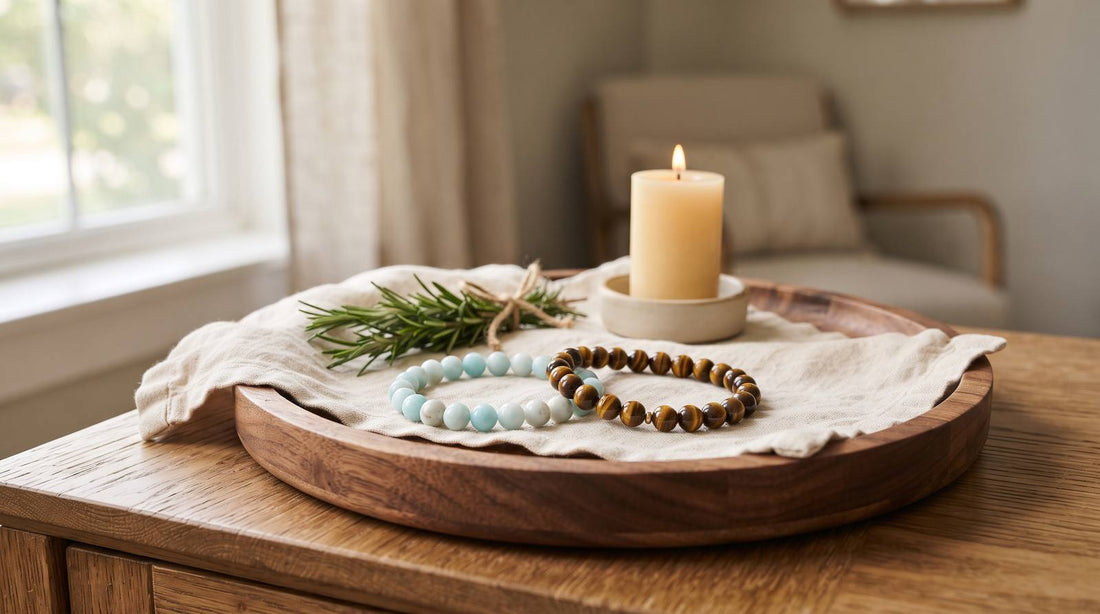 Amazonite and tiger eye bead bracelets on linen beside a candle and rosemary